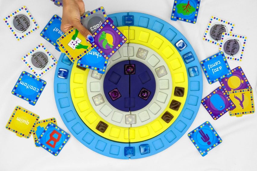 A photograph from above of a circular board game in tones of yellow and blue, with accompanying cards in the same tones.