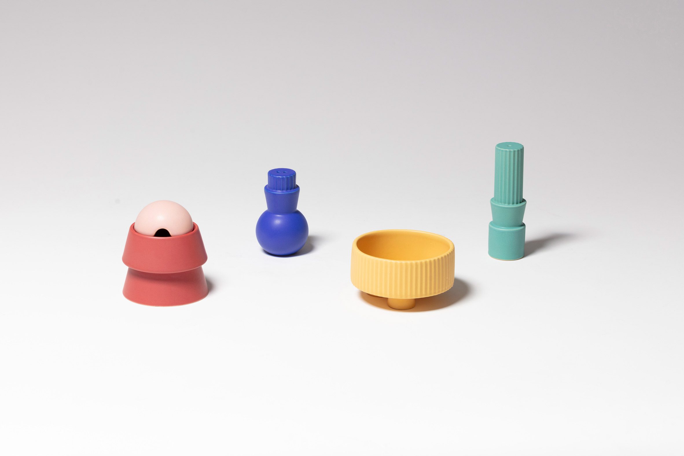 A photograph of ceramic bowls and vases in tones of pink, blue, yellow and green.