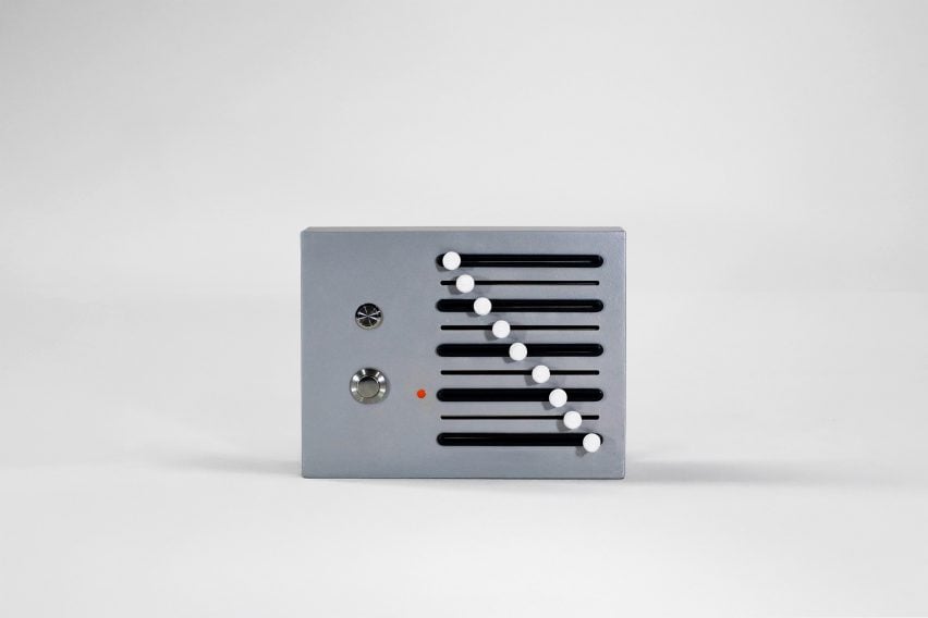 A photograph of a musical tool, shaped like a box with mechanic controls on it, in tones of grey, white and black.