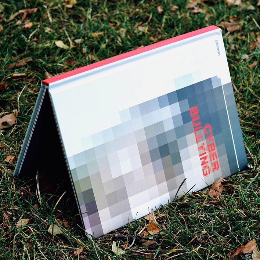 A photograph of an upside down book in tones of blue, grey and red on top of green grass.