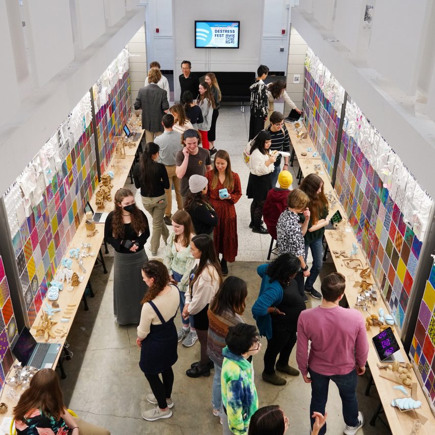 A photograph from above of a room with white and multicoloured walls, with a large group of people in it interacting with one another.