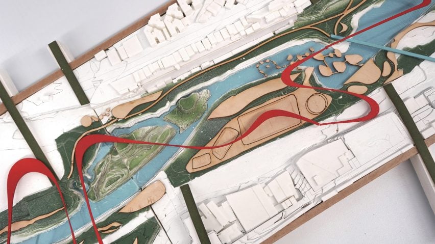 A photograph from above of an architectural model of a water filtration system, in tones of red, green and blue, among white buildings.