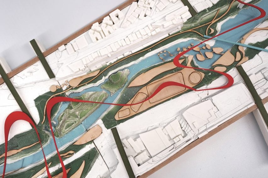 A photograph from above of an architectural model of a water filtration system, in tones of red, green and blue, among white buildings.