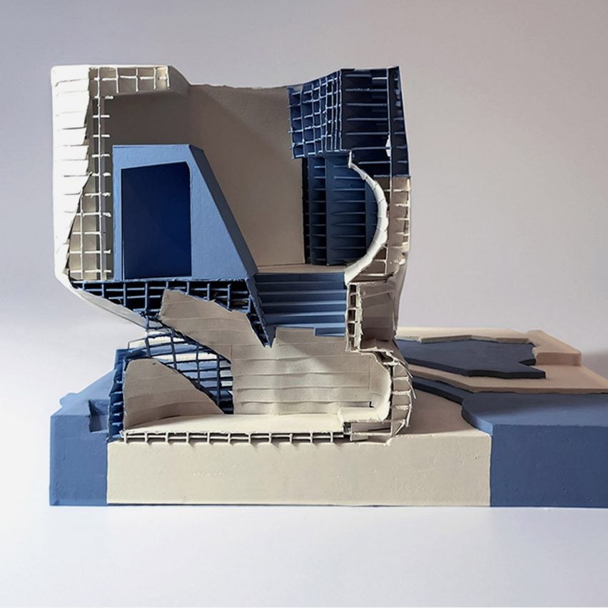 A photograph of an architectural model in tones of white and blue with a square structure.