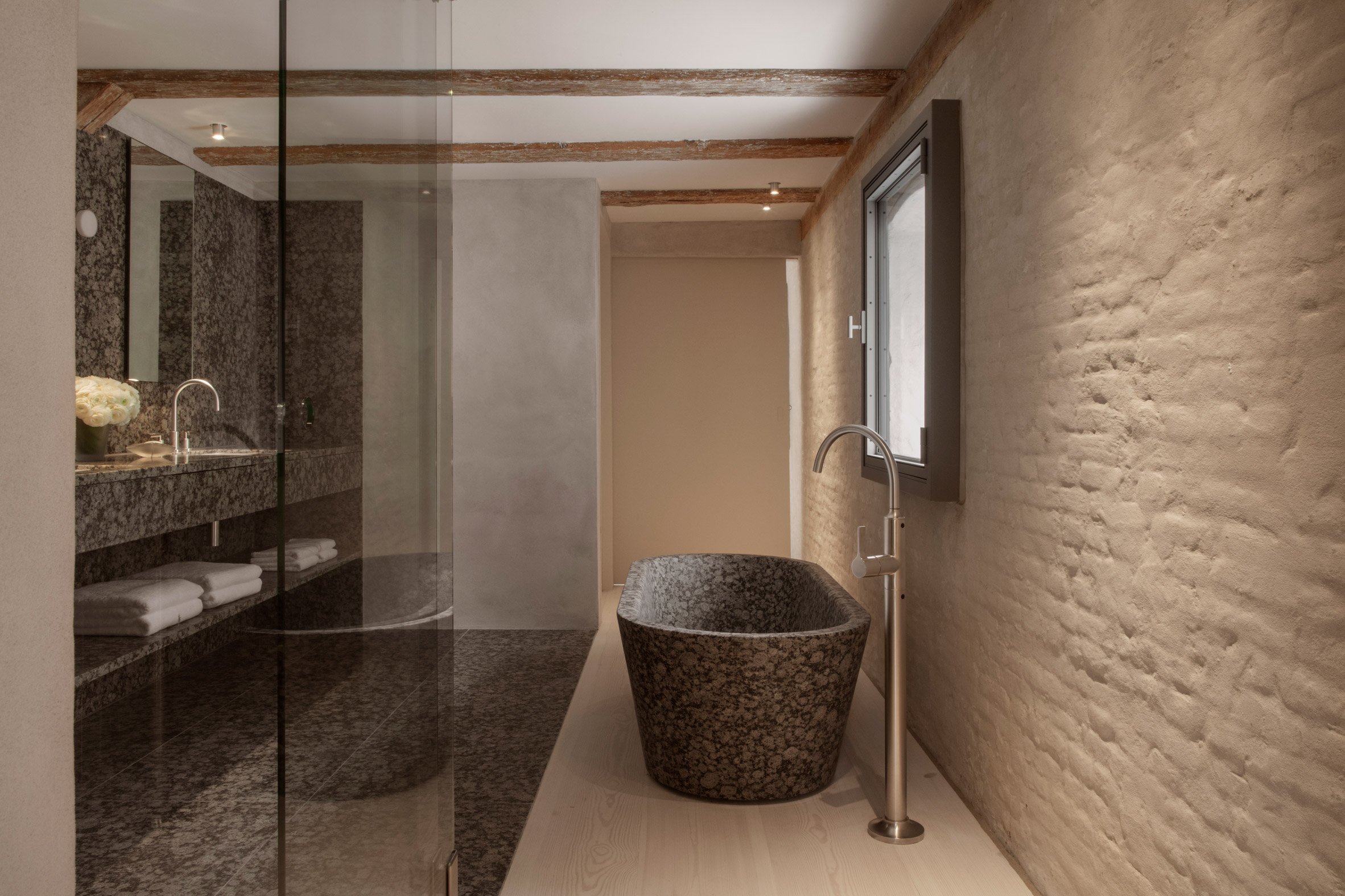 Brown granite freestanding bath and exposed brick walls 