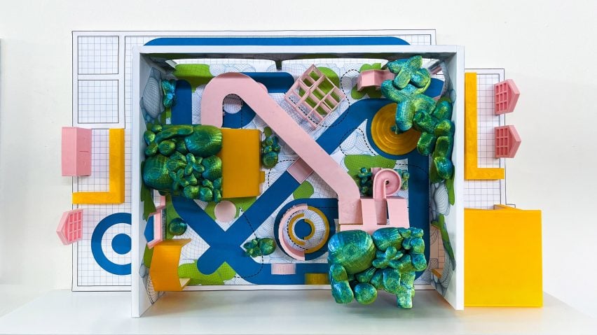 A photograph of an architectural model from above of a playground design, which features tones of pink, blue, green and yellow.