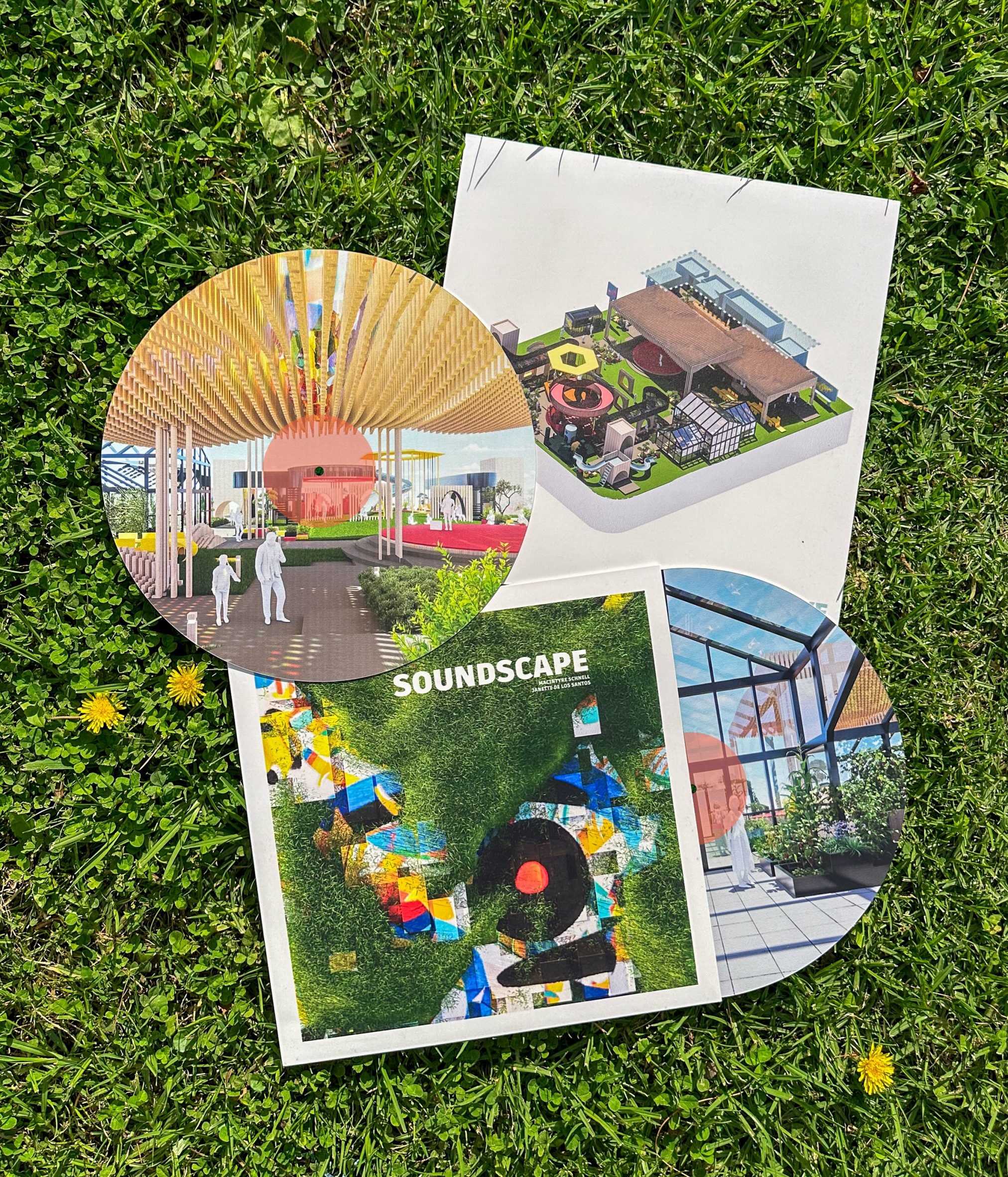 A photograph of printed designs for record sleeves and vinyl discs, which have visualisations of a soundscape centre printed onto them in multiple colours. The designs are laid against green grass.