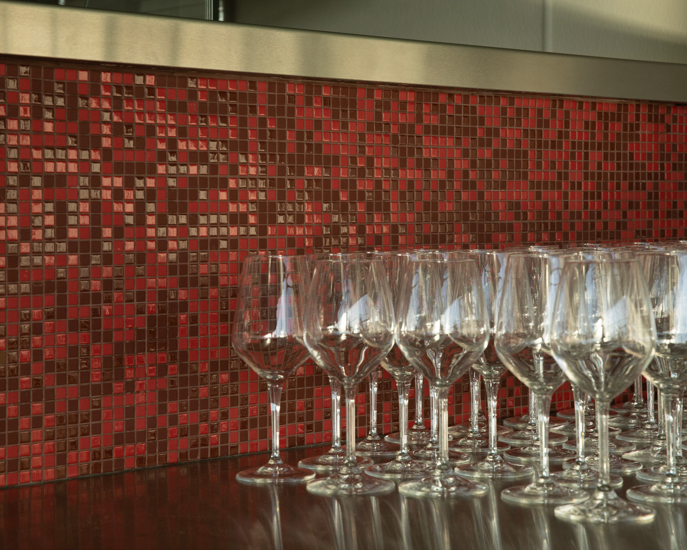 Tiny red and burgundy tiles behind rows of wine glasses