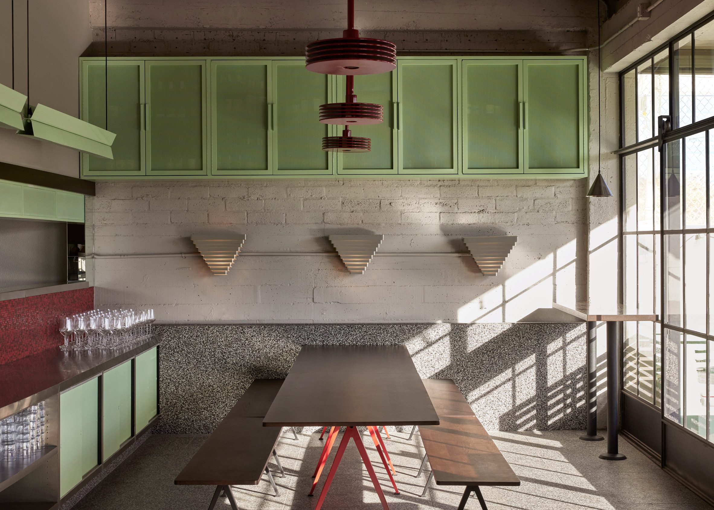 Pizzeria interior with picnic bench seating, speckled surfaces and pistachio-coloured cabinets