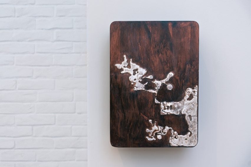 A photograph of a wooden vehicle charging block mounted onto a wall, in tones of brown with a silver pattern on it.