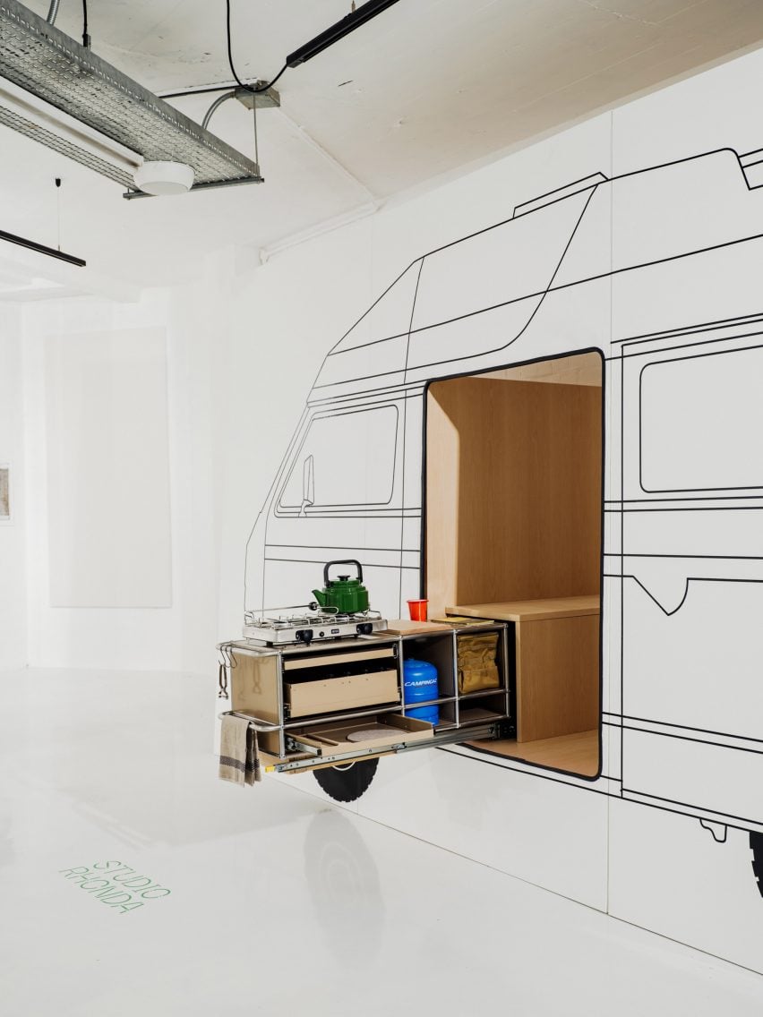 A photograph of a storage unit coming out of a white wall – illustrated around it in black is a camper van, detailing how the storage unit it intended to be a pull out feature of the van.