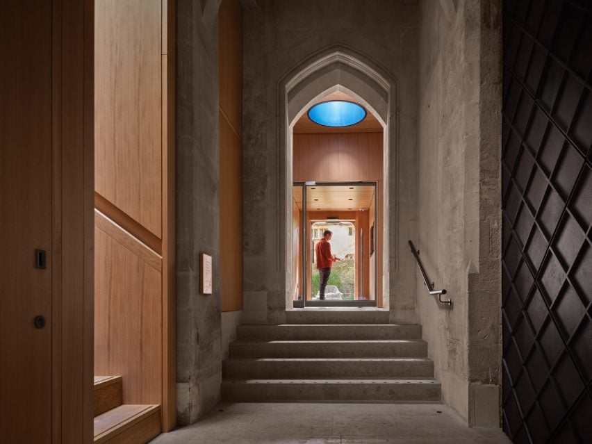 A photograph of the inside of a church in warm tones of beige and brown, with a person in a doorway.