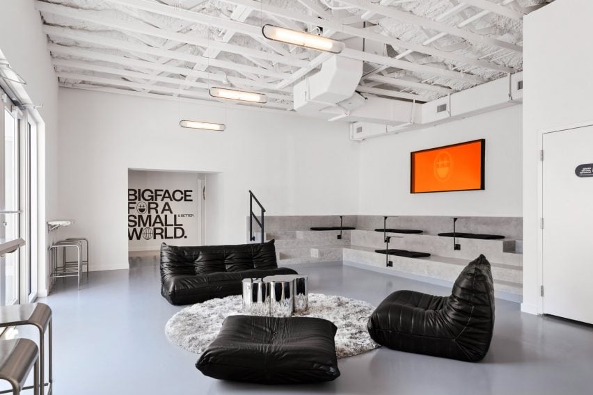 A seating area comprising black leather sofas and built-in concrete bleachers