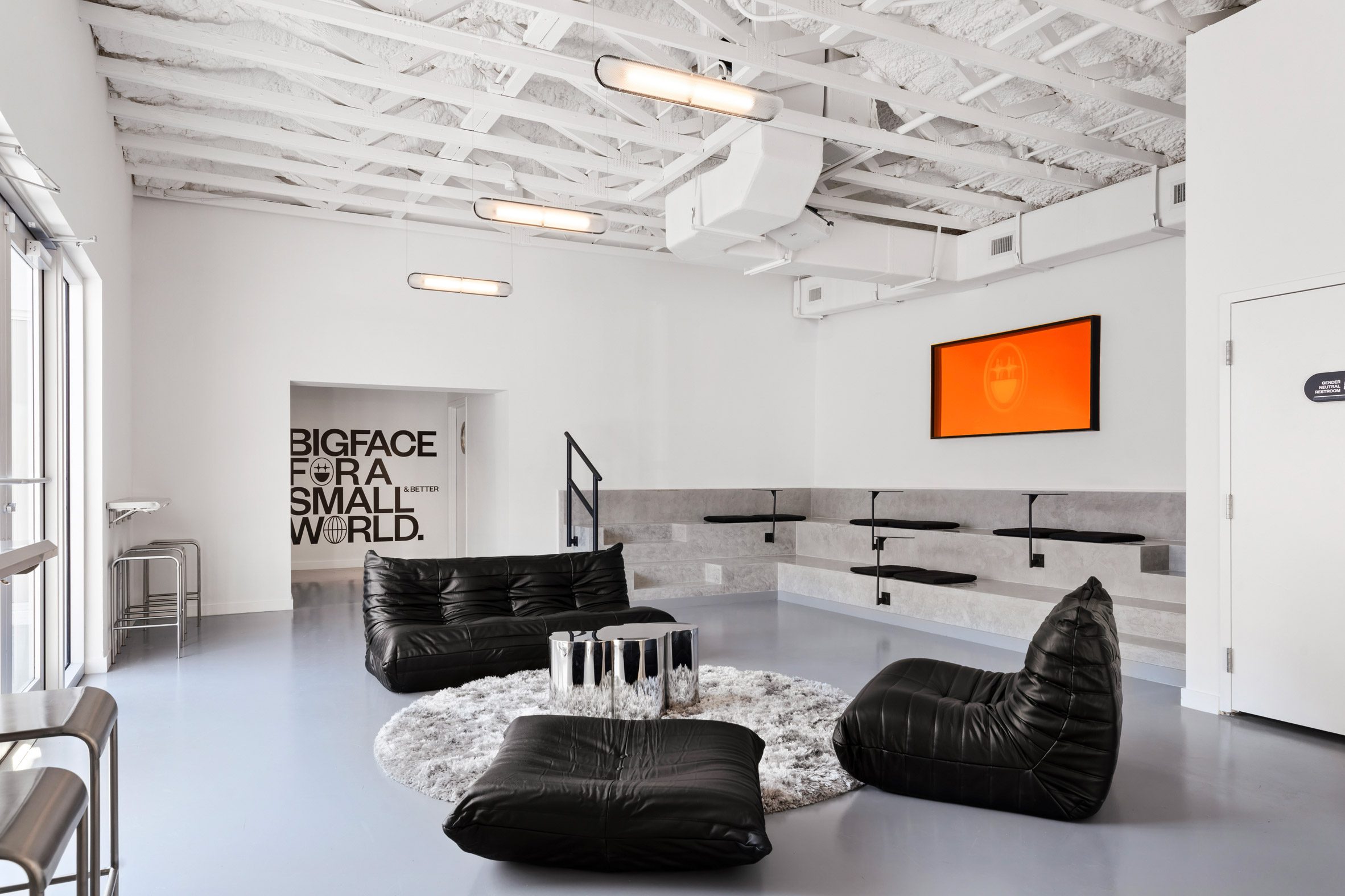 A seating area comprising black leather sofas and built-in concrete bleachers