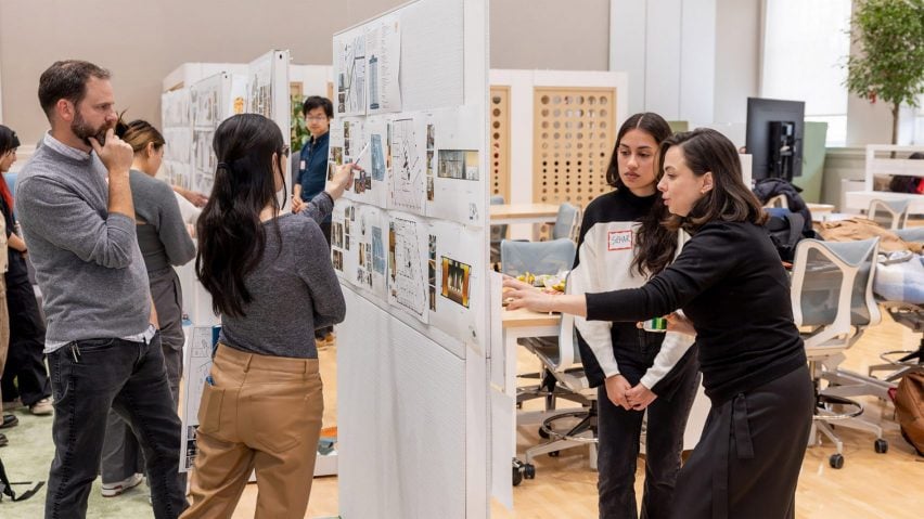 A photograph of students and tutors discussing their work at in a university.