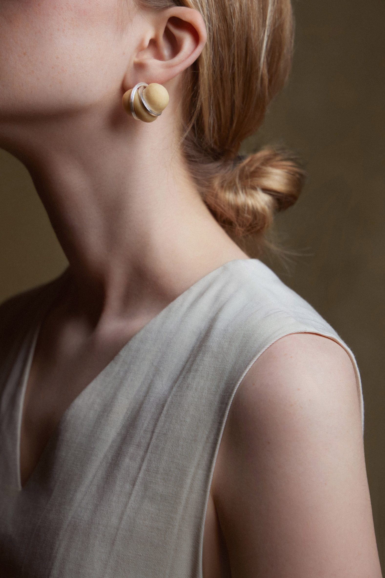 Photo of a woman from the shoulders up wearing earrings made of small baked bread dough wrapped in a metal wire frame