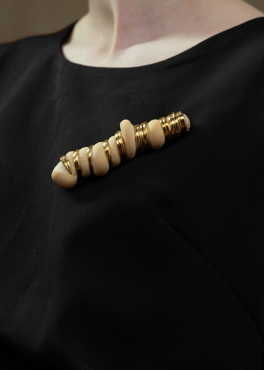 Brooch with baked golden bread dough bulging out of twisted metal wire in a long baguette shape from the Rising jewellery collection by Cindy Xinyi Wu