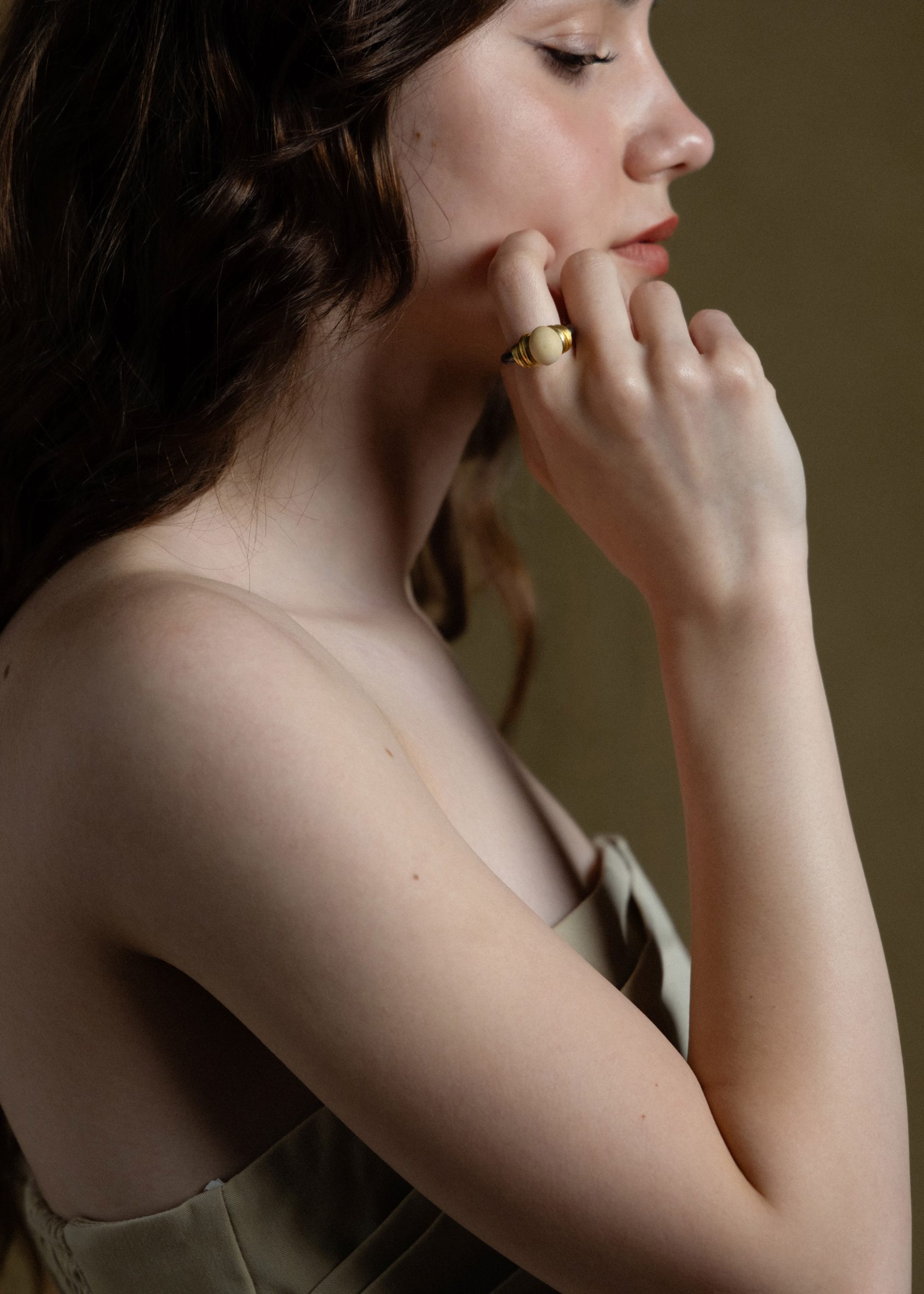 Profile photo of a woman raising one hand to her cheek. A silver ring with a small bread dough centrepiece by Cindy Xinyi Wu is on her pointer finger 