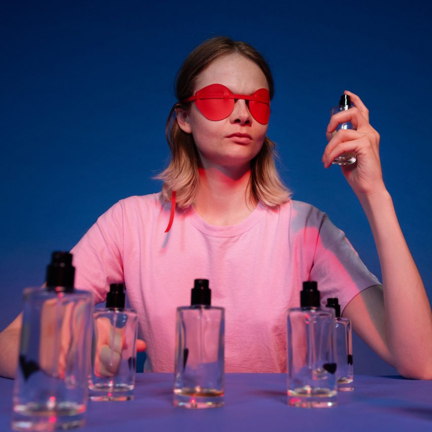 a person wearing a blindfold, spraying perfume