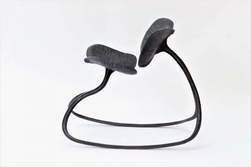 A photograph of a rocking chair in tones of black against a white backdrop.