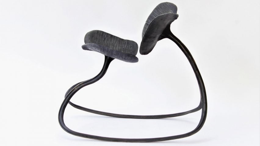 A photograph of a rocking chair in tones of black against a white backdrop.