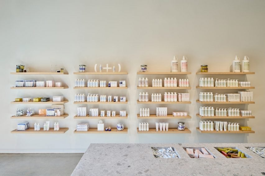 Malin+Goetz products displayed against a blank wall on white oak shelves