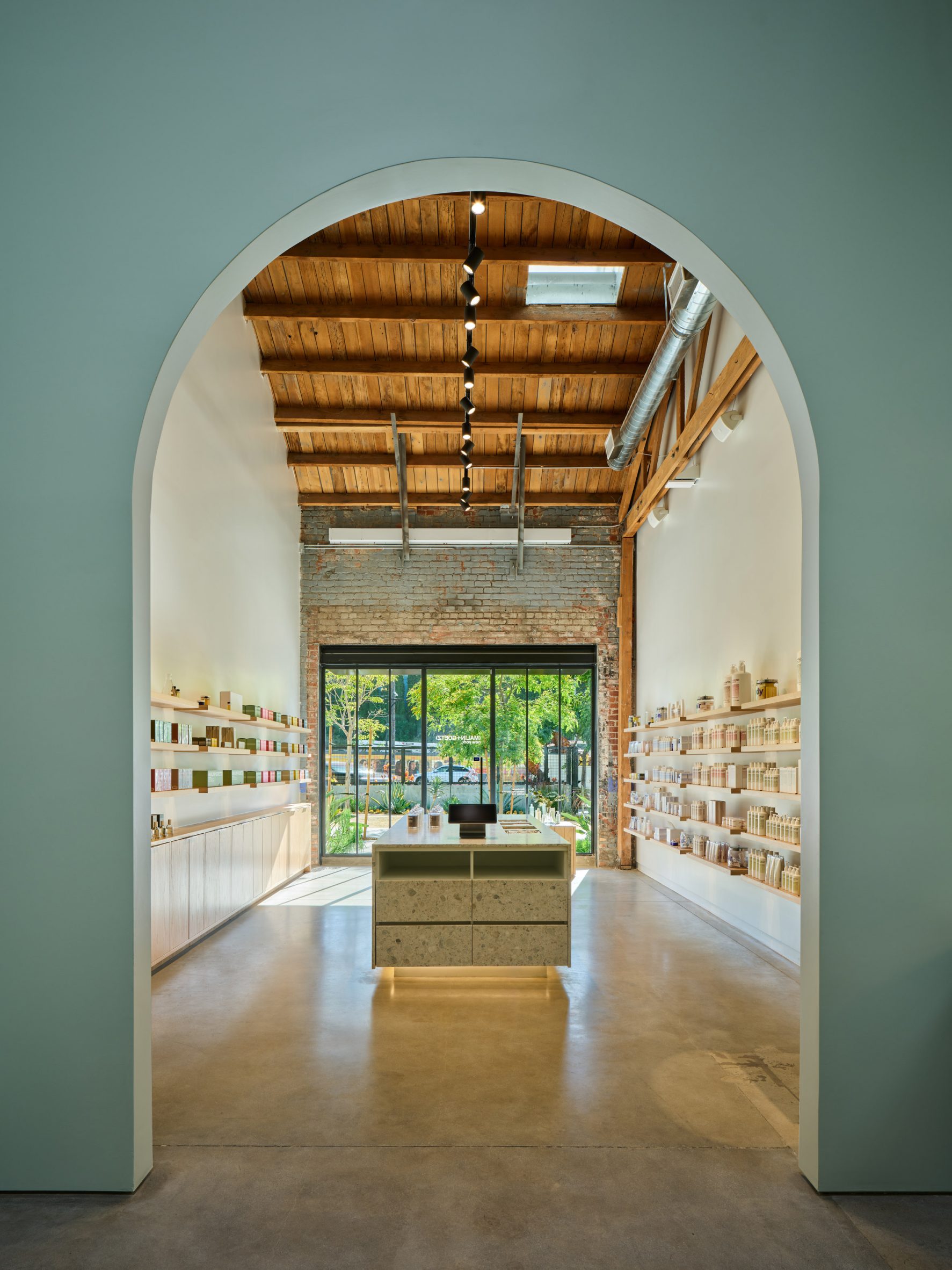 View through a green archway to a room with an exposed brick facade and wooden ceiling