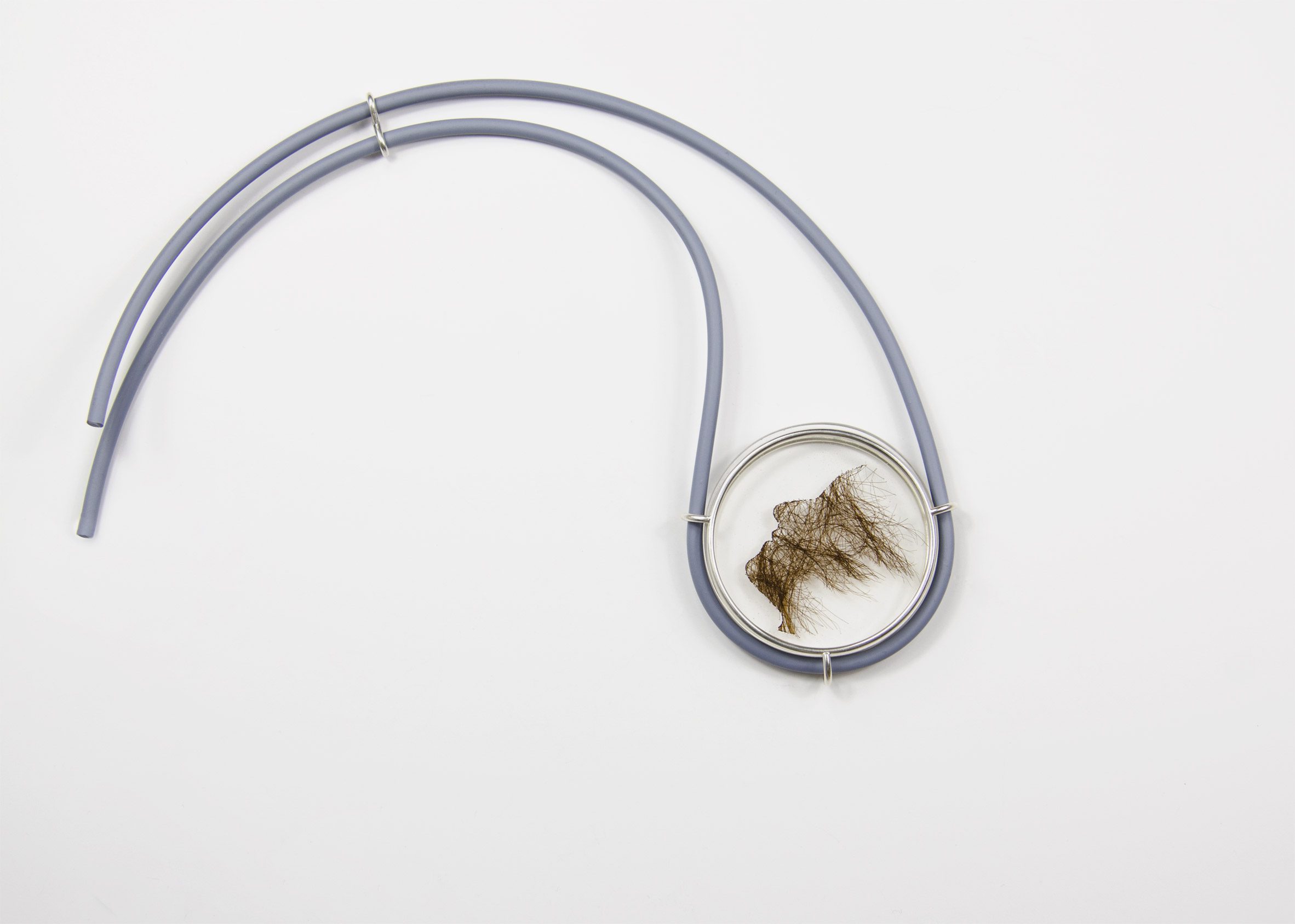 A photograph of a glass dish with brown hair inside. The dish is attached to a blue wire.