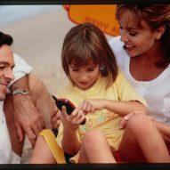 Promotional photo from the 1990s of a man and woman holding a girl using a phone