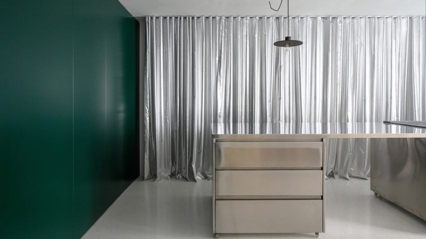 Room with dark green wall and silver curtains