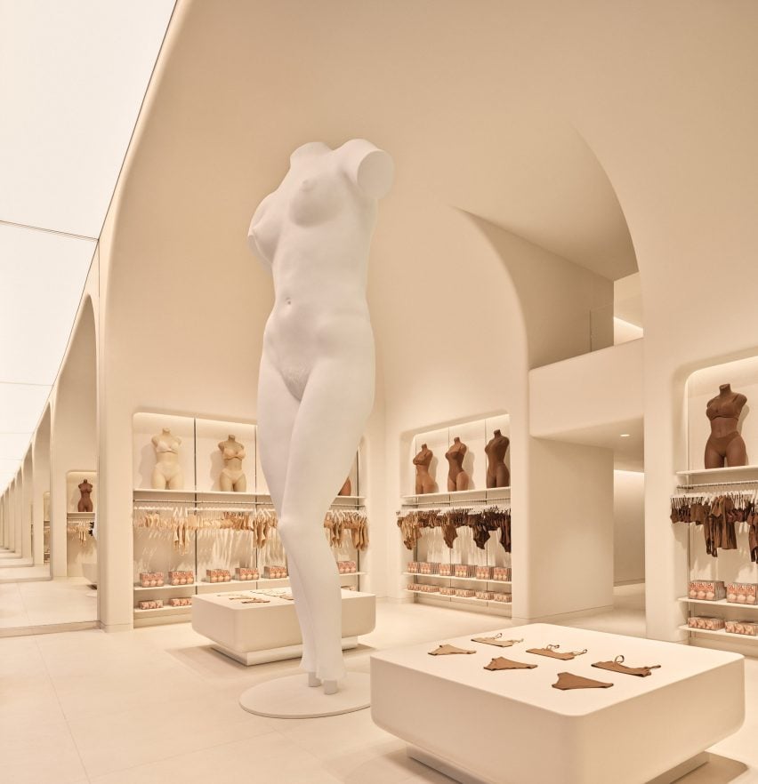 Nude-toned store interior with a giant mannequin in the centre