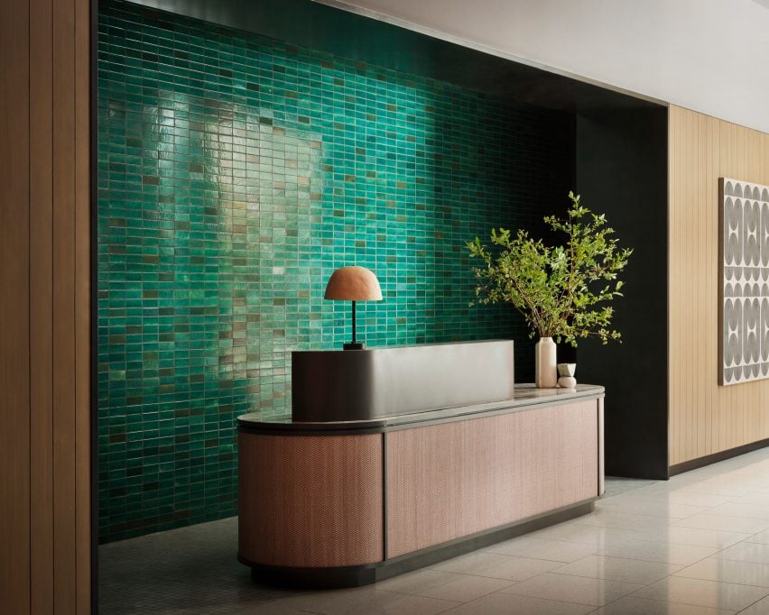 Reception desk wrapped in pink leather with green tiles behind