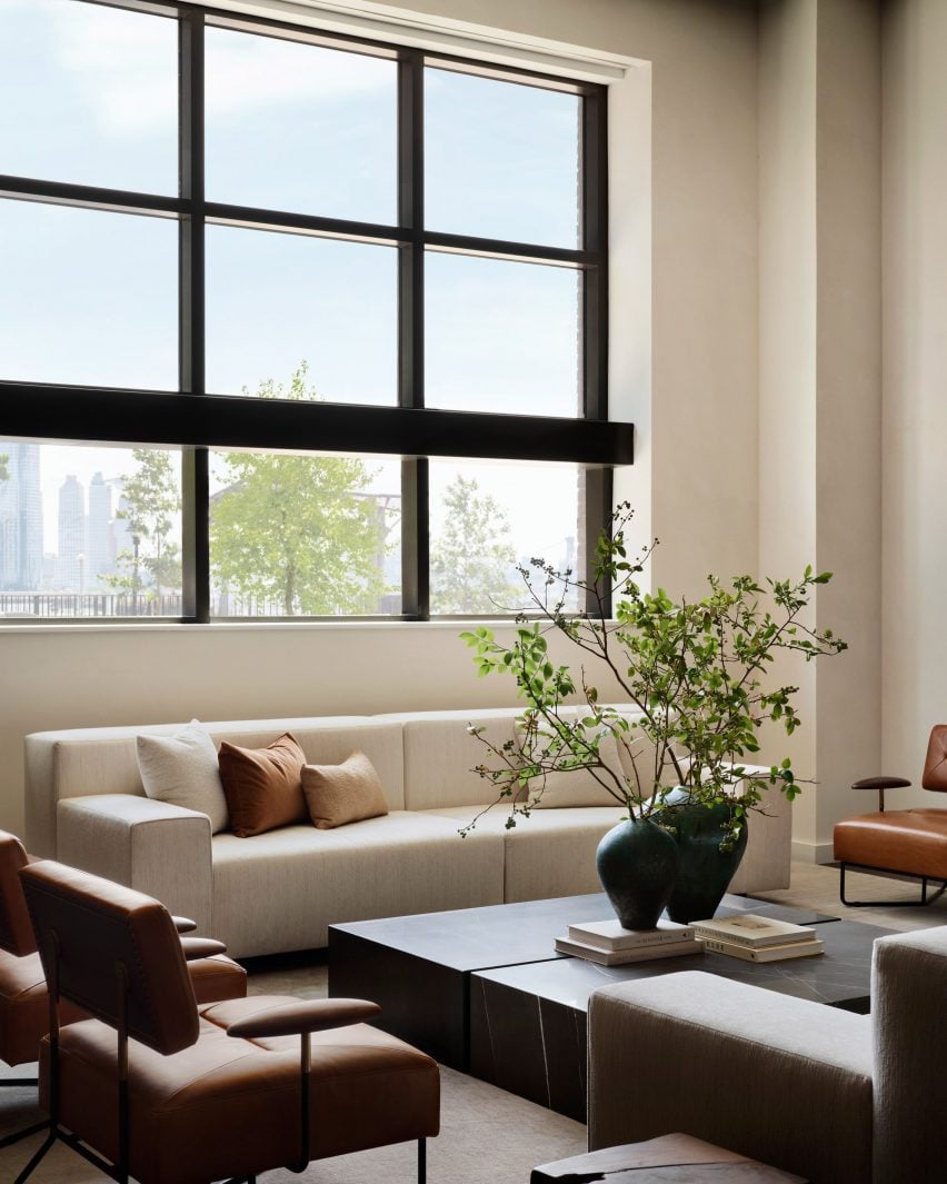 Neutral furniture and decor below a large loft-style window