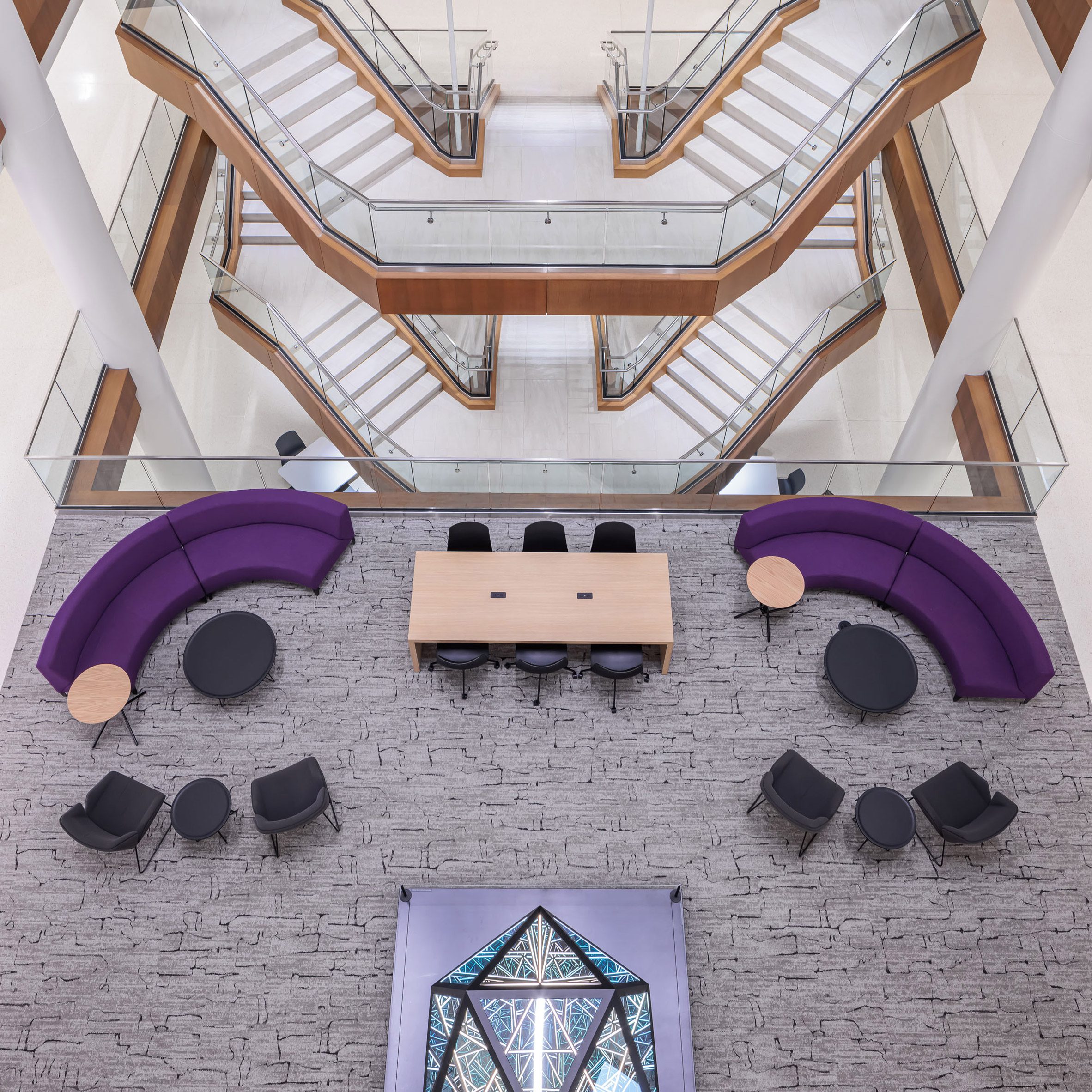 Looking down on a staircase linked by cantilevered mezzanine landings and a seating area