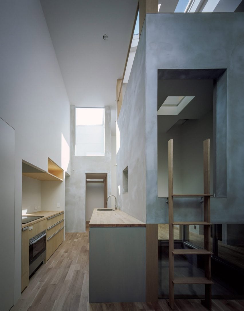 A photograph of a house consisting of grey concrete and square structures, illuminated by natural light from skylights.