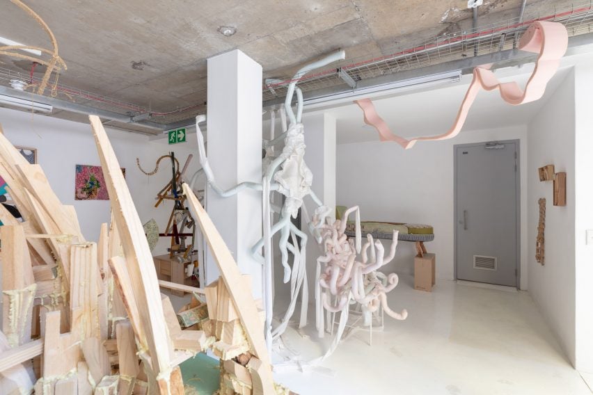 A chair made of pale, pastel-coloured tentacle-like foam pieces sits within a gallery exhibition