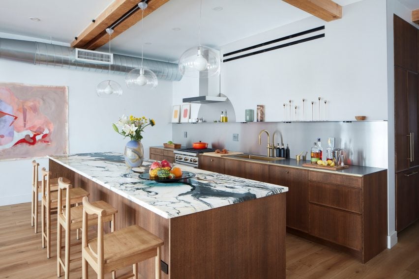 Kitchen with a stainless ⁣steel counter, backsplash and floating shelf