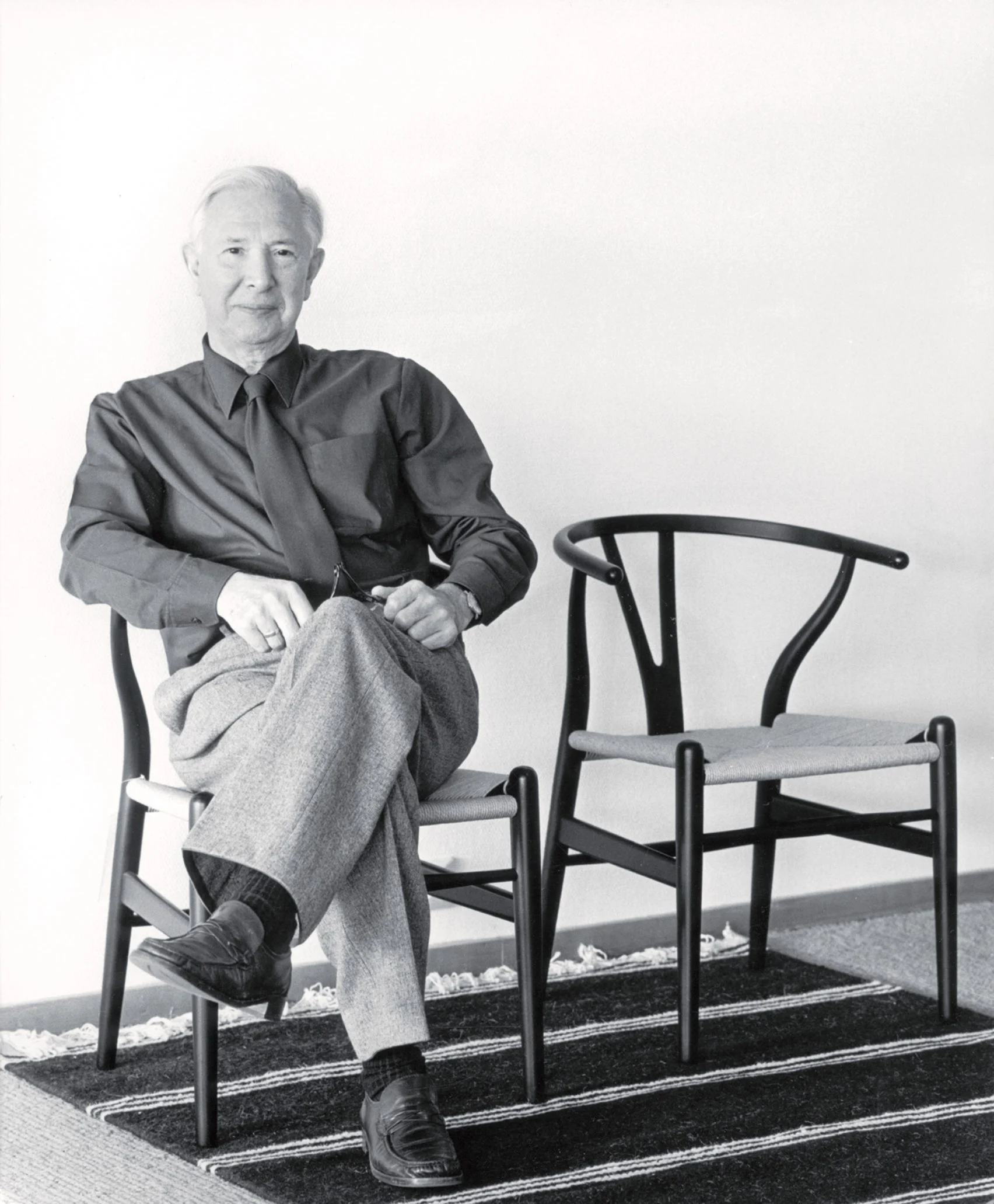 Hans J Wegner sitting next to Wishbone Chair