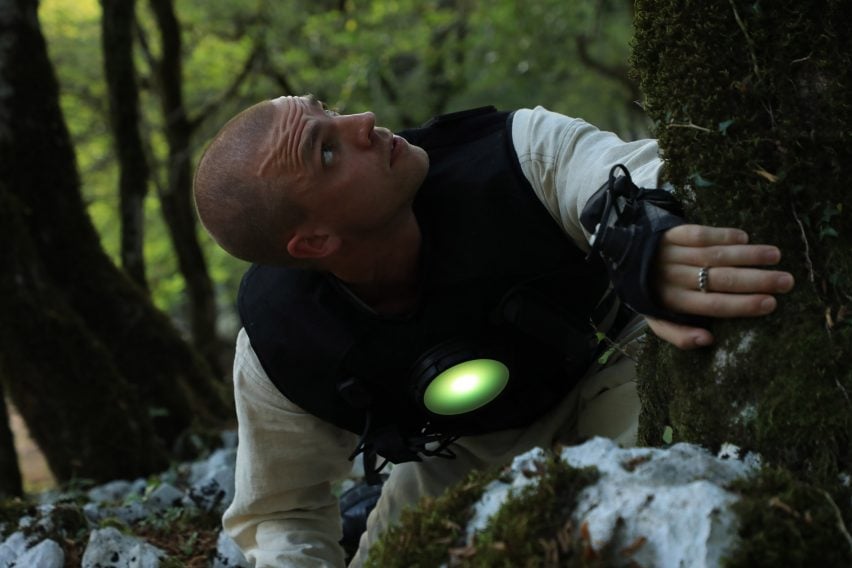 Photo of a man exploring a forest while wearing a black sensor-packed vest with a glowing green circular light over the heart