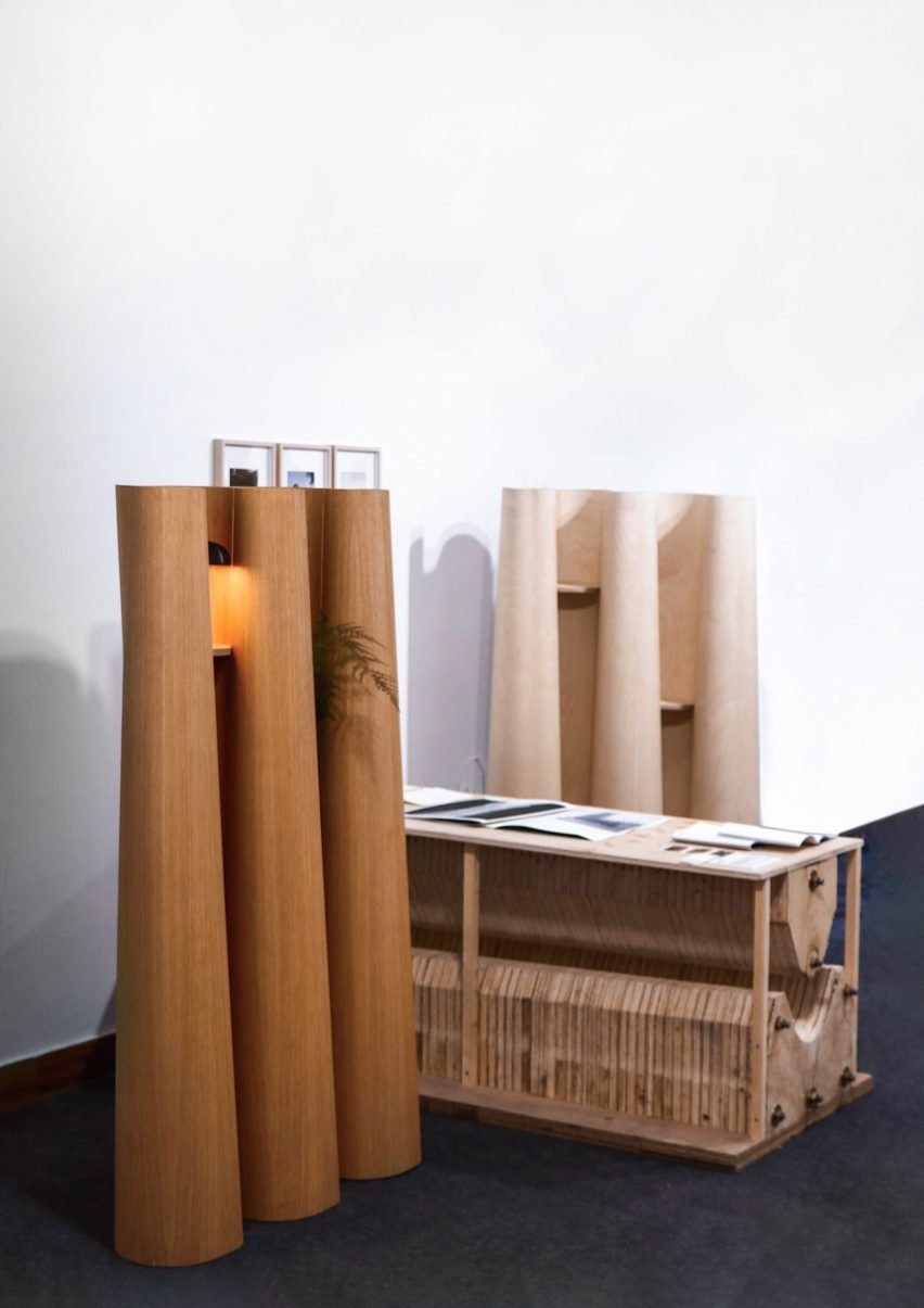 A photograph of three wooden structures in geometric shapes, placed against a white wall.