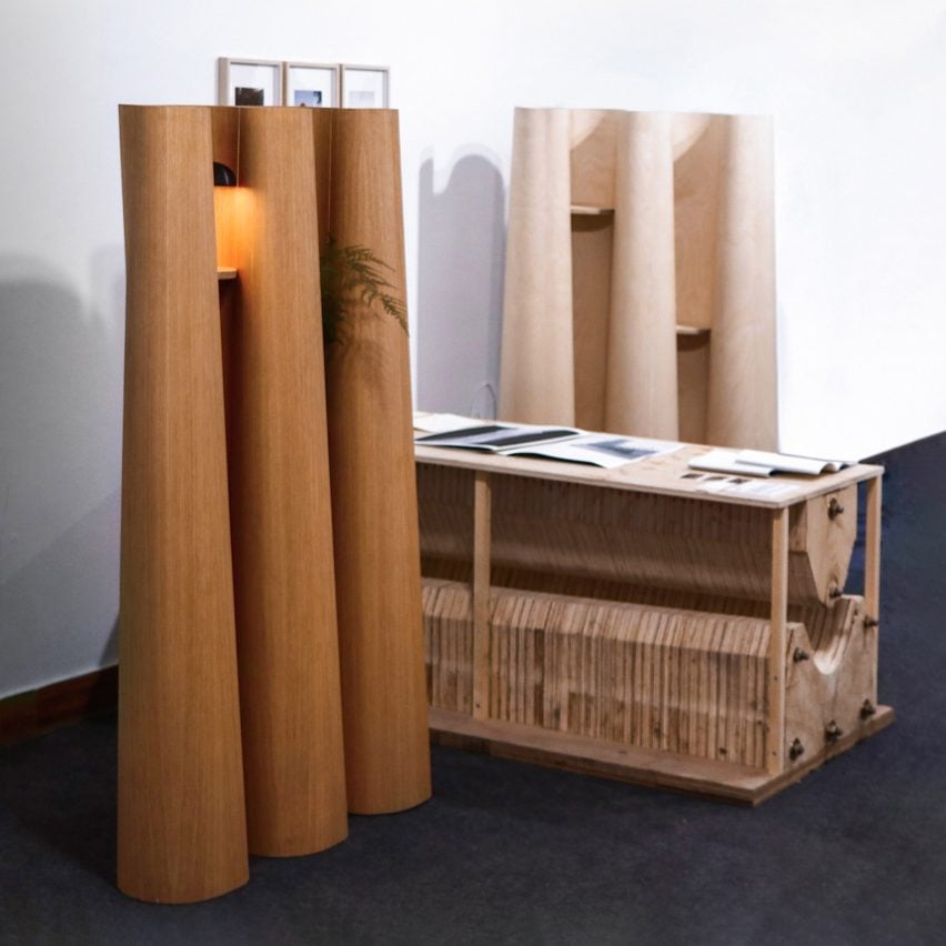 A photograph of three wooden structures in geometric shapes, placed against a white wall.