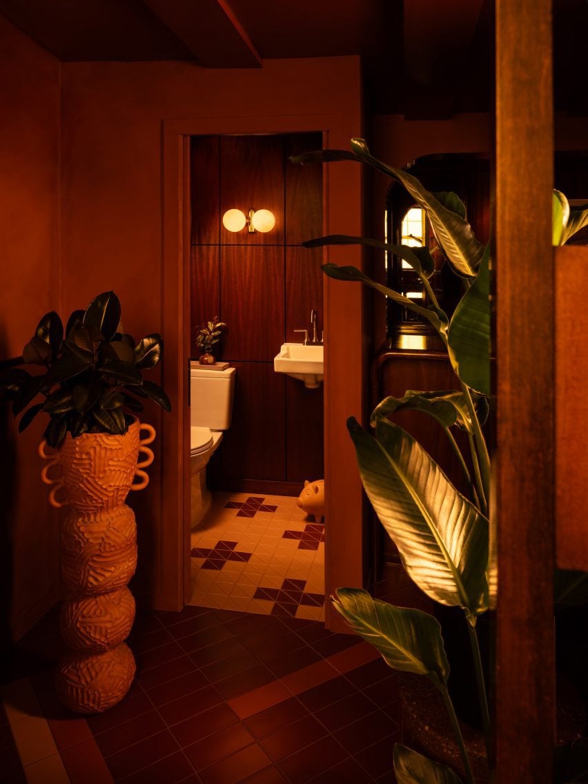 View into a bathroom with plants and a totem-like vessel in front