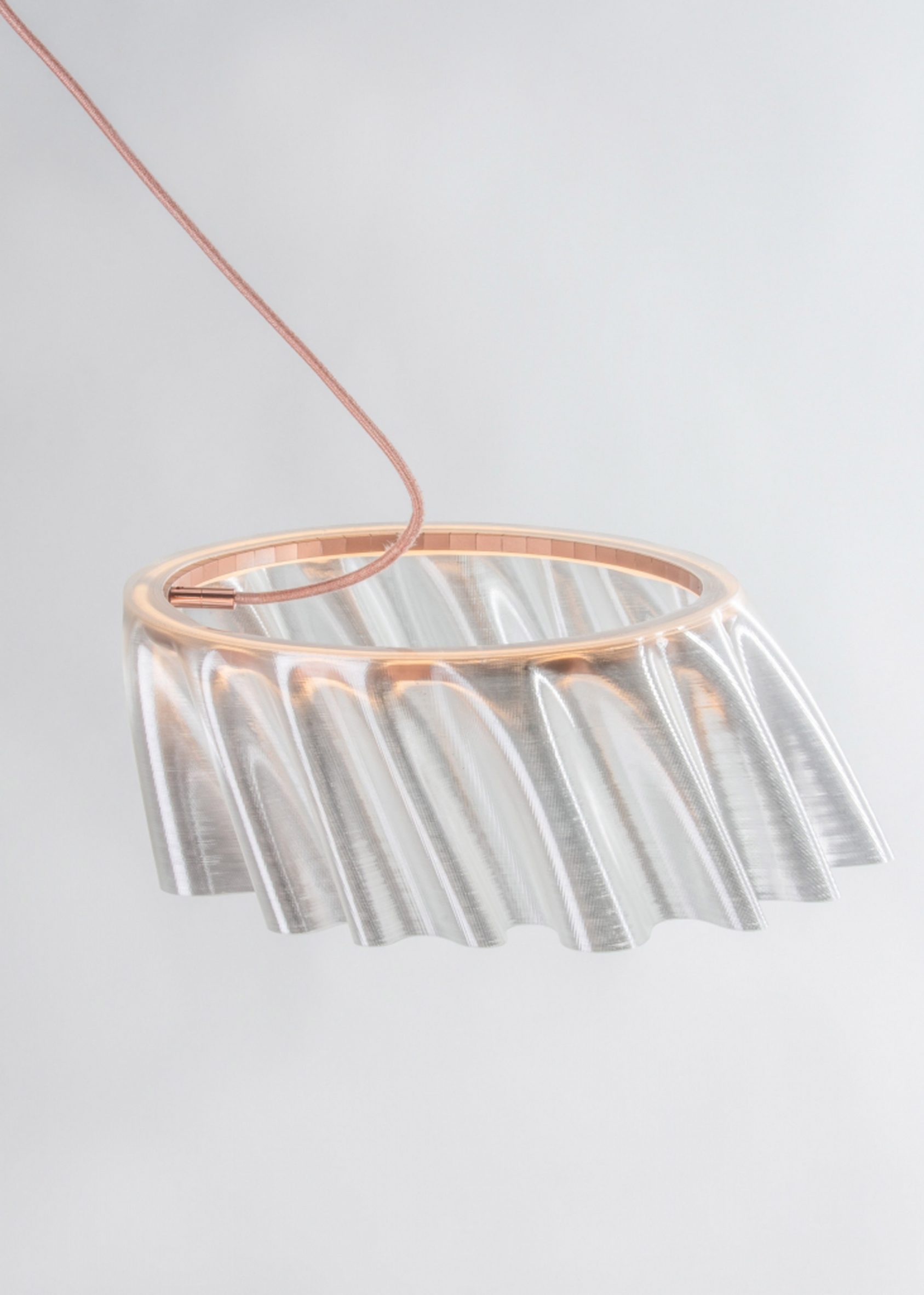 A photograph of a circular lamp with a gloss-textured translucent lampshade, and structured with a copper frame, along with a copper cord too.