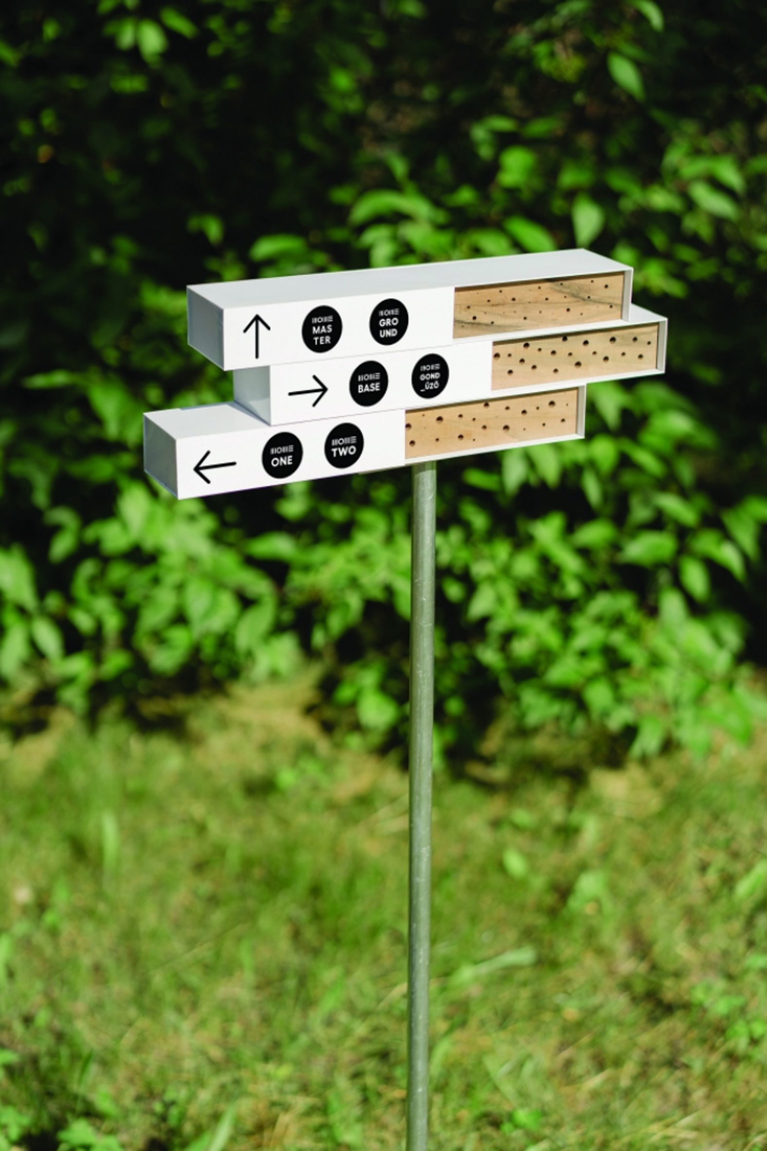 A photograph of a wooden block structure atop a pole, situated in a green field.