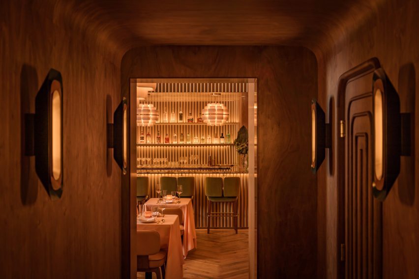 A corridor enveloped in walnut panels that curve onto the ceiling