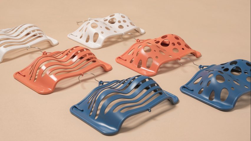 White, coral and blue Bras Up hangers displayed on a beige surface