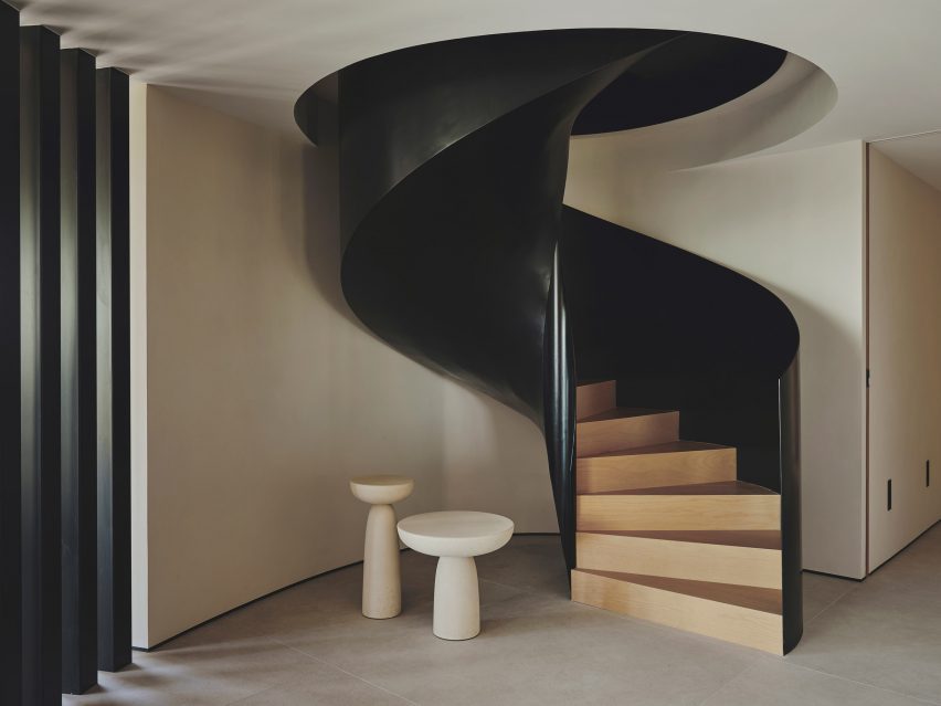 Photograph of a sculptural helical staircase made from black cast iron, with stairs made from natural wood