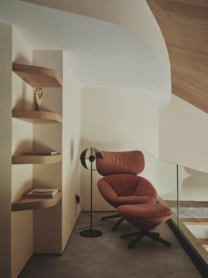 Photograph of a small reading area with a floor lamp and floating wooden shelves