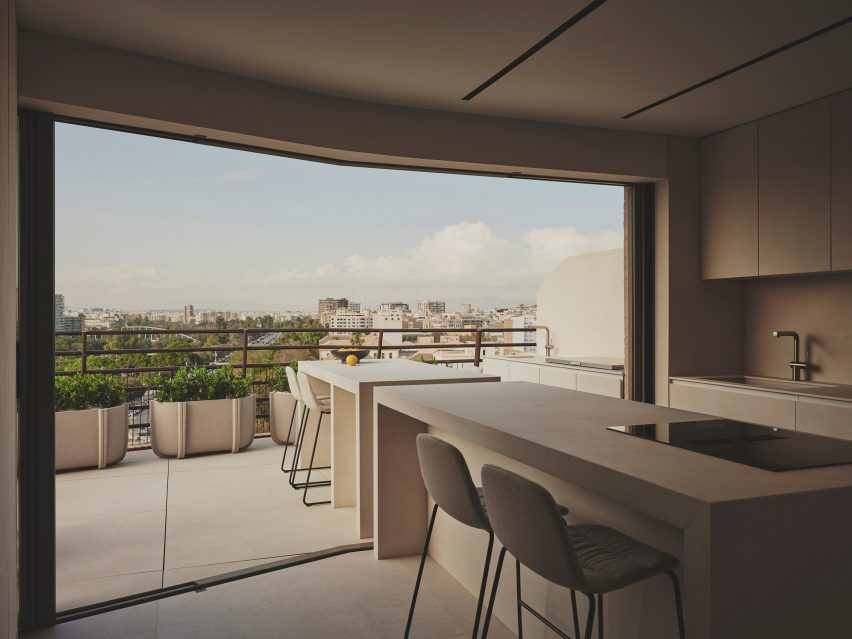 Photograph of an indoor and outdoor kitchen island separated by a large glass facade