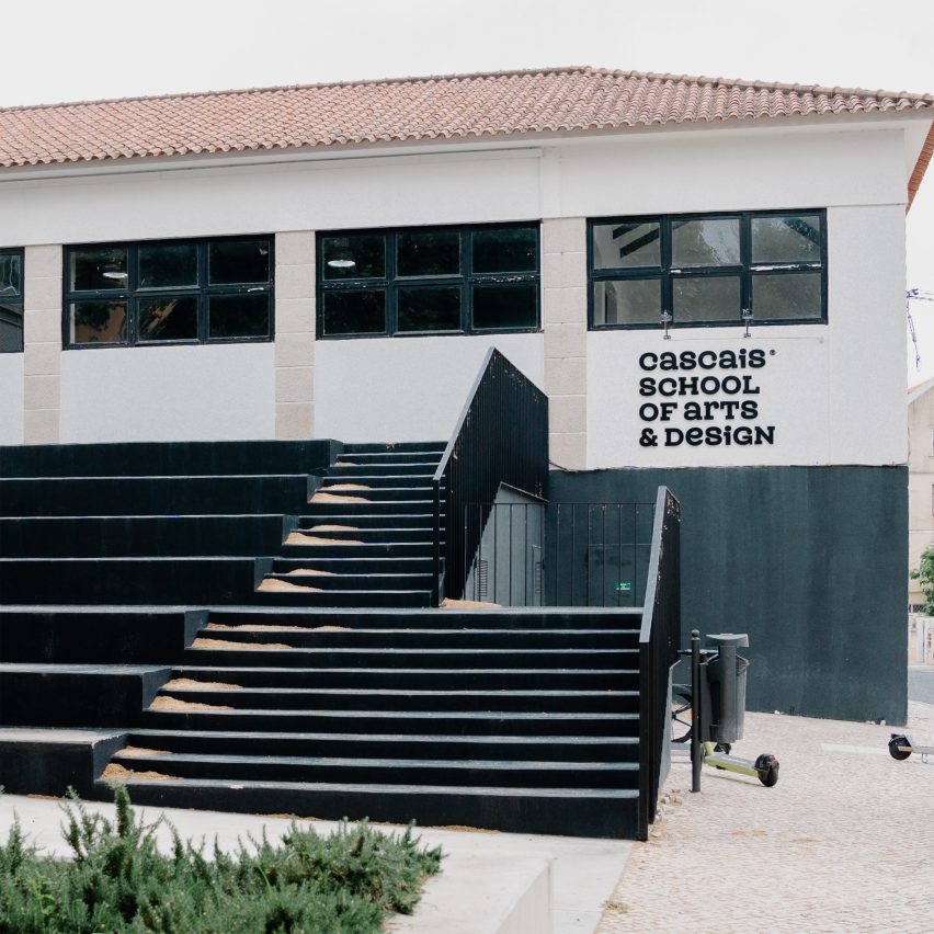 A photograph of a building in tones of white and black, with black steps leading up to it.